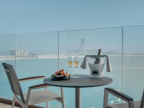 a table with two glasses of wine and a bowl of fruit at Mövenpick Resort Al Marjan Island in Ras al Khaimah