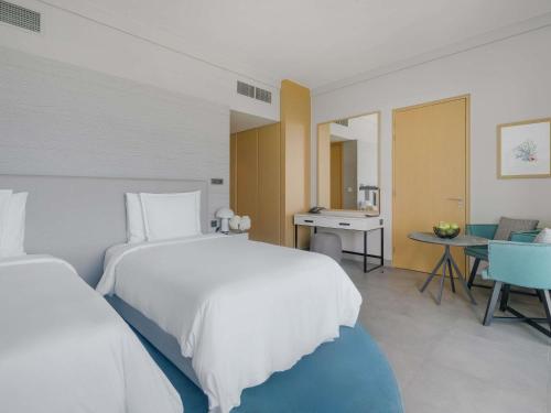 a bedroom with a large white bed and a table at Mövenpick Resort Al Marjan Island in Ras al Khaimah