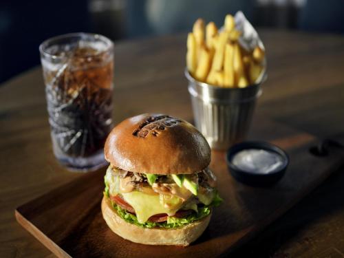 a sandwich on a wooden tray with french fries at Mövenpick Resort Al Marjan Island in Ras al Khaimah