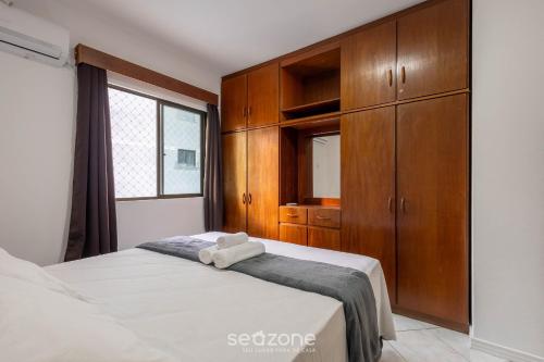 a bedroom with a bed with a wooden cabinet at Apto c/ varanda e churrasq. a 290m do mar CAU0199 in Meia Praia