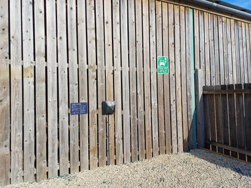 a wooden fence with two signs on it at Pear Tree Cottages in Wedmore
