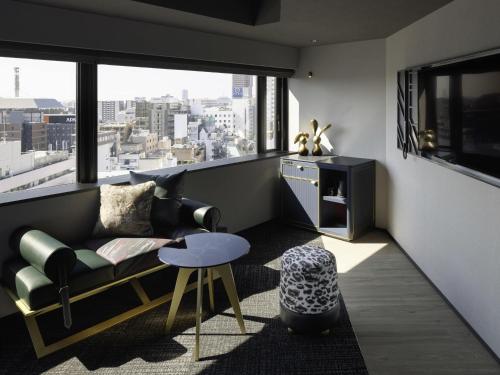 a living room with a couch and a large window at Mercure Tokyu Stay Osaka Namba in Osaka