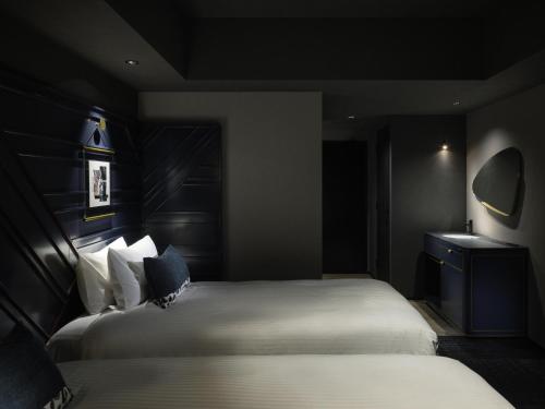 a bedroom with two beds in a dark room at Mercure Tokyu Stay Osaka Namba in Osaka