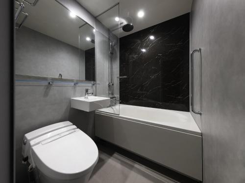 a bathroom with a toilet and a tub and a sink at Mercure Tokyu Stay Osaka Namba in Osaka