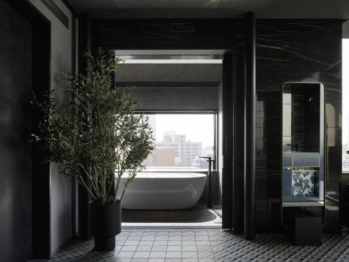 a bathroom with a tub and a potted plant at Mercure Tokyu Stay Osaka Namba in Osaka