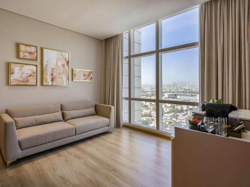 a living room with a couch and a large window at Movenpick Jumeirah Village Triangle in Dubai