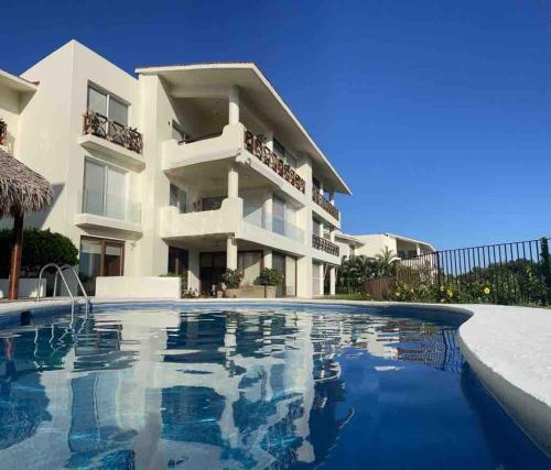 a villa with a swimming pool in front of a building at Departamento Cruz de Mar in Santa Maria Huatulco