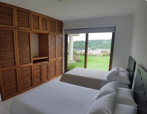 a bedroom with two beds and a large window at Departamento Cruz de Mar in Santa Maria Huatulco