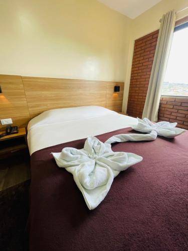 a hotel room with a bed with white towels on it at Hotel Garnier in Campos do Jordão