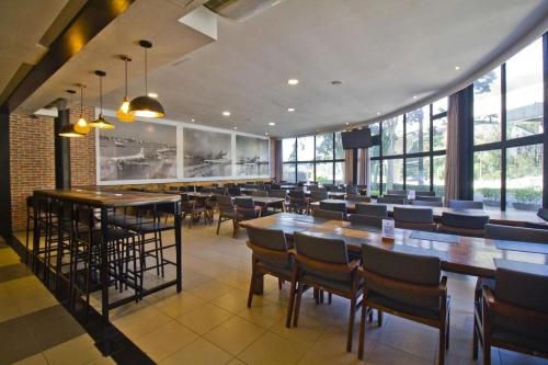 a restaurant with wooden tables and chairs and windows at Airfamily Congonhas in Sao Paulo