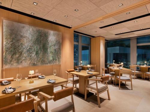 a restaurant with wooden tables and chairs and windows at AKI Hotel Hong Kong - MGallery Collection in Hong Kong
