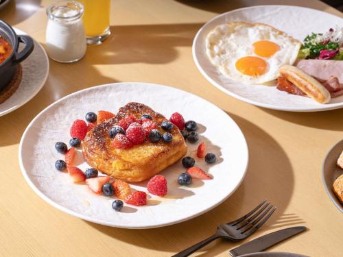 a table with two plates of breakfast food with pancakes and fruit at AKI Hotel Hong Kong - MGallery Collection in Hong Kong