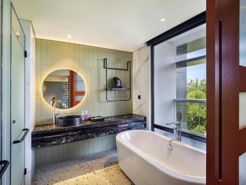 a bathroom with a tub and a sink at Tribe Bali Kuta Beach in Kuta