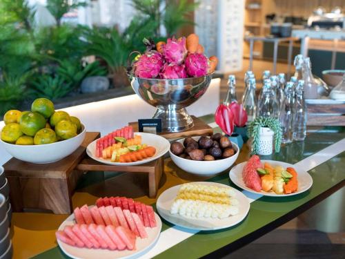 a table topped with plates of food and bowls of fruit at Tribe Bali Kuta Beach in Kuta