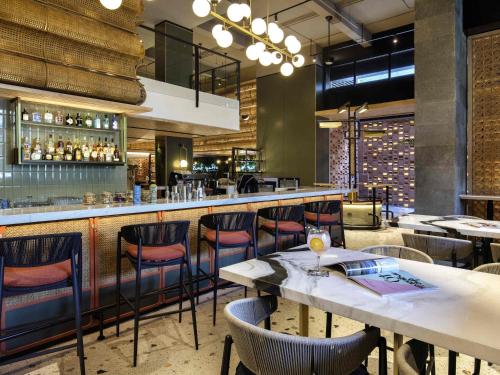 a restaurant with tables and chairs and a bar at Tribe Bali Kuta Beach in Kuta