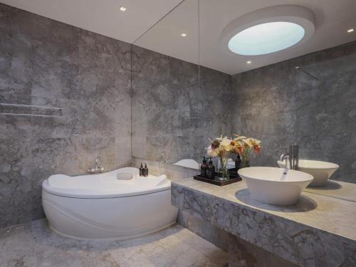 a bathroom with a large white tub and a sink at Peppers Seminyak in Seminyak