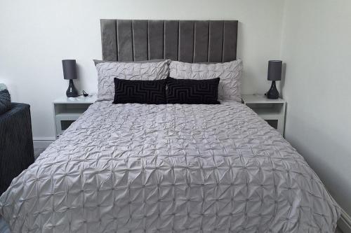 a large bed with a silver comforter and two lamps at Lodge - Sleeps 2 - Pet friendly - Parking - Patio in Sidcup