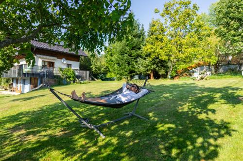 a person laying in a hammock in a yard at mirnockAHOI - familienfreundliches Ferienhaus für 4 Erwachsene, maritimes Bergerlebnis, Panoramablick von Terrasse und Balkon, Carinthia, Millstättersee in Ferndorf