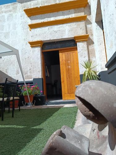 un bâtiment avec une porte en bois et une cour gazonnée dans l'établissement Barrio Sureño Hotel Boutique, à Arequipa