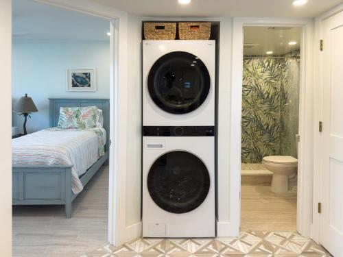 サニベルにあるLuxury Waterfront Condoのベッド付きの客室で、洗濯機と乾燥機が備わります。