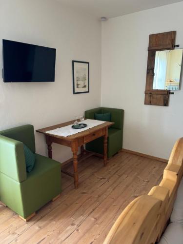 a living room with a wooden table and green chairs at Berggasthof Pension Sonnenalm in Hauzenberg