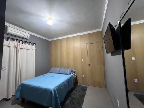 a bedroom with a blue bed and a flat screen tv at House Amorim 13 min Parque peão in Barretos