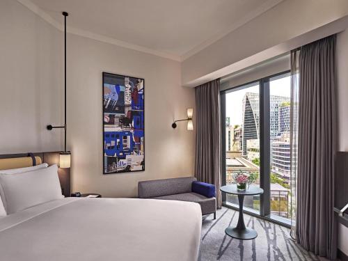 a hotel room with a bed and a chair and a window at Pullman Singapore Orchard in Singapore