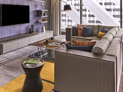 a living room with a couch and a tv at Pullman Singapore Orchard in Singapore