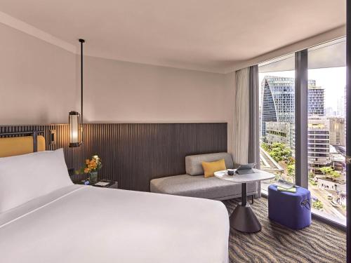 a hotel room with a bed and a couch at Pullman Singapore Orchard in Singapore