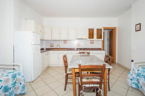 a kitchen with a table and chairs and a refrigerator at I Ciottoli Dello Ionio in Mascali
