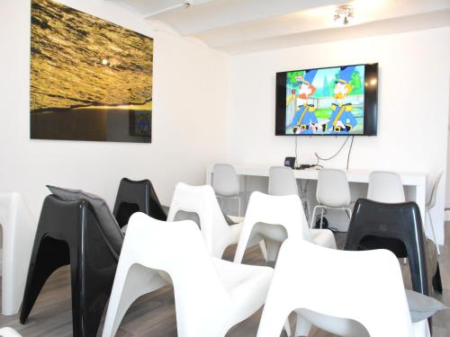 a conference room with white chairs and a flat screen tv at Group Escape by Molignée River in Denée