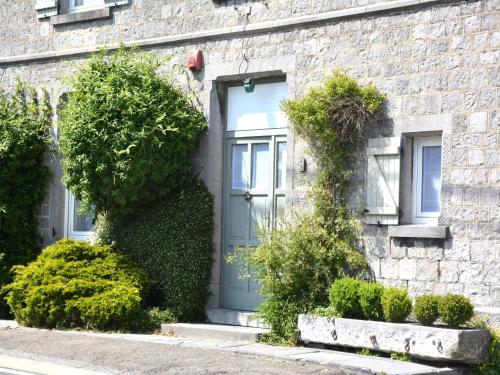 a brick house with a blue door and bushes at Group Escape by Molignée River in Denée