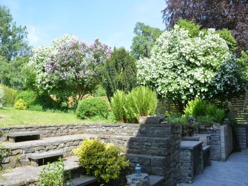 a garden with a stone retaining wall and trees at Group Escape by Molignée River in Denée