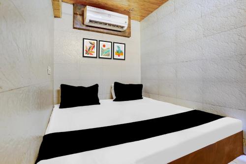 Una pequeña habitación con una cama blanca con almohadas negras. en Collection O Ambedkar Chowk Ulhasnagar, en Bombay