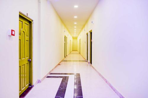 an empty hallway with yellow doors and a tile floor at Hotel O Howrah Botanical Garden in Kolkata