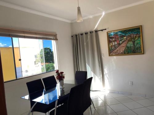 a dining room with a table and chairs and a window at Apartamento 2 quartos in Caetité