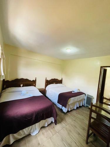 a hotel room with two beds and a mirror at Hotel Garnier in Campos do Jordão