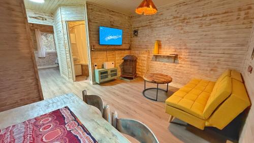 a living room with a yellow couch and a table at Ruimyz cabbin in Manot