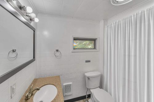 a white bathroom with a toilet and a sink at Right Field All Star Baseball Rentals in Oneonta