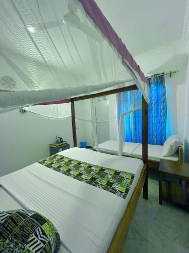 a bedroom with two beds and a canopy bed at Karibu House Paje in Paje