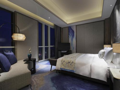 a hotel room with a bed and a couch at Pullman Yantai Center in Yantai