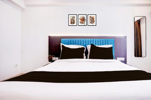 a bedroom with a large white bed with a blue headboard at Collection O Navi Mumbai Formerly IVY Hotel in Mumbai
