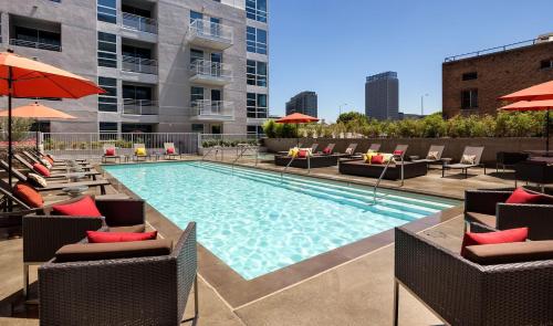 a swimming pool with chairs and umbrellas on a building at Hollywood Luxury Retreat I Pool Views I Jacuzzi I Fitness Center I Free Parking! in Los Angeles