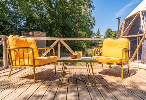 two yellow chairs and a table on a deck at Petit dôme in Biziat