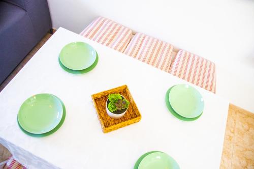 a white table with green plates and a plant on it at El Arenal de Famara by Escape Home in Famara