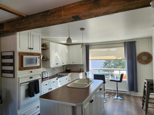 een keuken met witte kasten en een groot raam bij Chalet Lac Édouard cozy in La Tuque