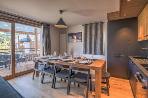 a dining room with a wooden table and a kitchen at Appartement Havre des Alpes - Welkeys in Megève