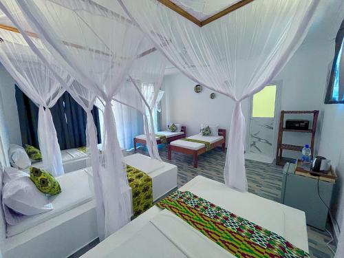 a bedroom with white curtains and a room with a bed at Karibu House Paje in Paje