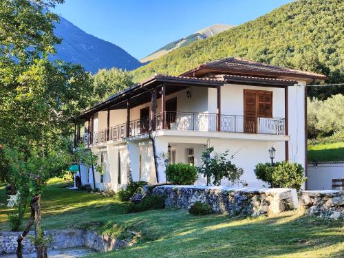 a white house with a balcony and mountains in the background at Tenuta Le Pietre Bed & Breakfast in San Donato Val di Comino
