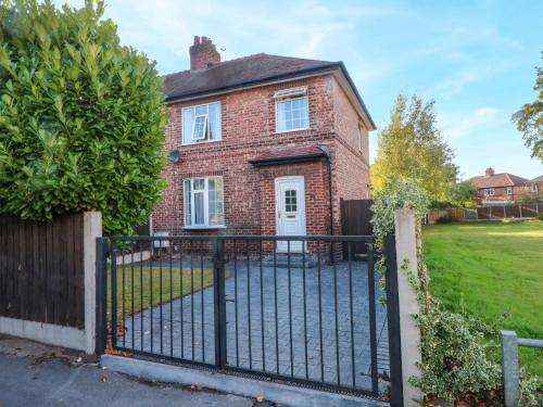 a brick house with a black iron fence at Ash House in Altrincham